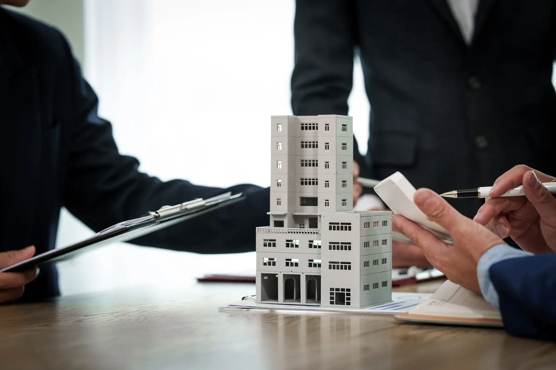 immostark - Menschen an einem Tisch mit einem Immobilien-Modell: Bauträger-Service